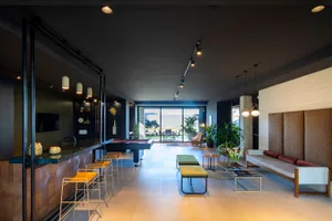 Modern living room featuring a concrete bar, stylish furniture, and plants.