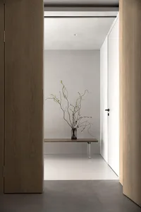 Minimalist entryway featuring wooden bench and concrete floor.
