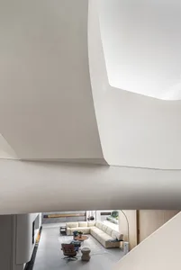 A modern, contemporary living room with concrete walls and flooring, featuring minimalist furniture and natural light.