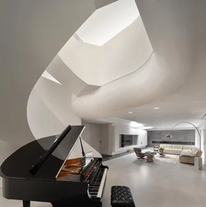 A spacious, minimalist residential interior with concrete walls, a grand piano, and a modern fireplace.