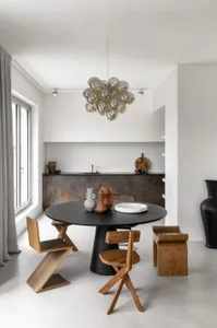 Modern minimalist kitchen with a round black table, wooden chairs, and a cluster of bubble chandelier