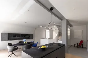 A modern residential kitchen with black concrete countertops and a black island, featuring sleek design elements and a minima