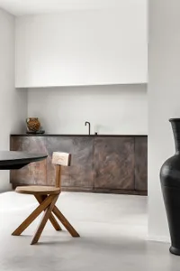 A modern kitchen with metallic wood cabinets and a black table with a wooden stool.