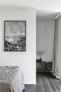 A modern minimalist bedroom featuring a bed with silver bedding and a marble wall.