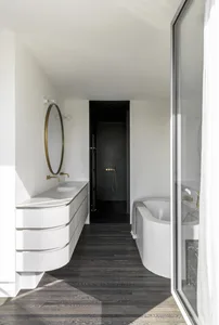 A modern bathroom with white marble countertops and black concrete walls.