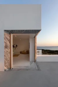 Modern minimalist residential interior with marble finishes, featuring a sofa, coffee table, and abstract artwork.