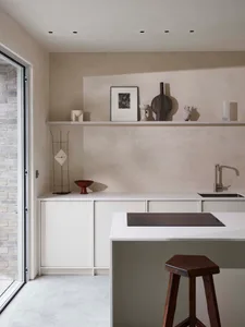 Modern, minimalist residential kitchen with white marble countertops and cabinets, featuring a central island and a sleek, co