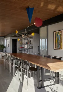Modern industrial dining room with a long wooden table, metal chairs, and a unique hanging light fixture.
