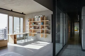 A modern office with a floating wooden shelf and a light wooden desk.