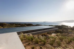 Modern floating concrete infinity pool overlooking the ocean and mountains.