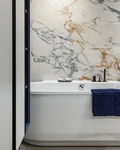 Modern minimalist bathroom featuring white marble walls and a white bathtub with blue towels.