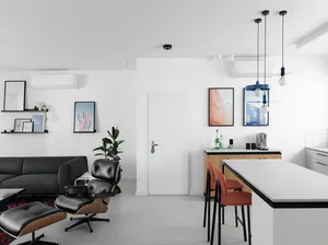 A modern, minimalist kitchen with white cabinetry, pendant lights, and an open layout.