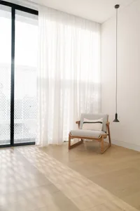 A minimalist living room with a wooden floor and fabric furniture.