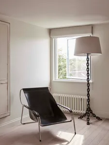 A minimalist living space featuring a black leather lounge chair, metallic chain lamp, and white floor plan.