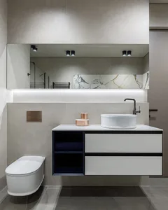Modern bathroom with a concrete and marble vanity, a white toilet, and a large mirror above the sink area.