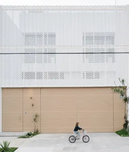 Modern building with perforated metal facade and large wooden doors