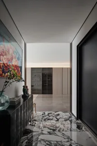 A modern, minimalist entrance hallway with a marble floor and black furniture.