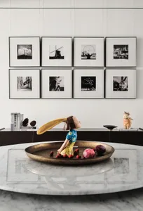 A modern interior featuring decorative art pieces and a metallic relish dish filled with colorful fruits.