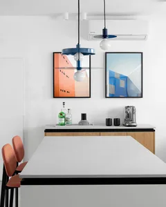 Modern kitchen with concrete countertops, wooden cabinets, and metallic pendant lights.