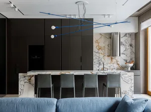 Modern kitchen featuring a marble countertop with a steel range hood and black cabinetry.