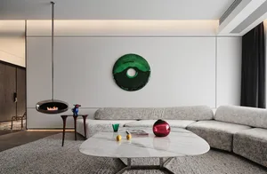 A modern living room featuring a marble coffee table, a leather corner sofa, and a round green mirror on the wall.