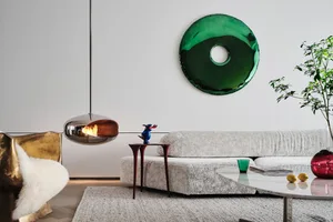 A modern living room featuring a textured fabric sofa, a minimalist coffee table, and a unique round green mirror.