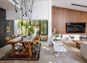 Modern living room featuring a wood-paneled wall and large windows showcasing a green outdoor space.