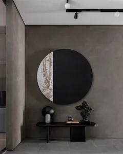 A minimalist entrance lobby featuring a metal table with various decorative items and a large circular artwork with a black a