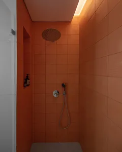 Modern shower enclosure with terrazzo tile walls, featuring a wall-mounted showerhead and handheld sprayer.