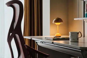 A minimalist home office with a modern desk, chair, and table lamp.