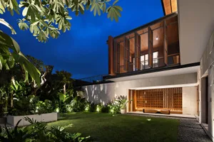 夜間視角的極簡住宅花園，搭配混凝土牆面、木質百葉與茂密綠植。