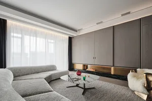 A modern living room featuring a plush grey sectional sofa, a marble coffee table with decorative items, and a wall-mounted c