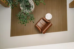 A modern lobby with a wooden floor, a brown leather chair, and a white circular side table.