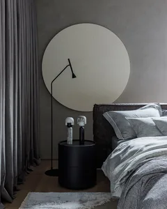 Modern minimalist bedroom with a gray fabric headboard, light gray bedding, and a textured gray rug. The room features soft,