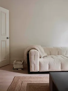 A modern, cozy living room with a soft, neutral-toned sofa and a minimalist coffee table, featuring a stack of magazines or b