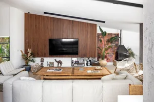 A modern industrial living room with a wooden wall, leather furniture, and a large screen TV.