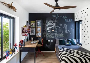 A modern, black and white themed bedroom with a chalkboard wall, a bed with zebra print bedding, and superhero figurines on t