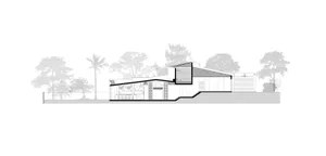 Modern house with concrete exterior and large windows against a tree-lined background.