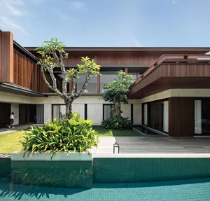 A modern residential architecture with wooden exterior walls, surrounded by a suburban garden featuring a pool and lush green