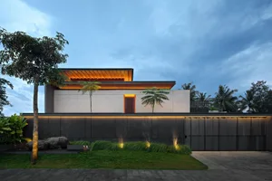 Modern house with concrete exterior at dusk with illuminated pathway and palm trees.