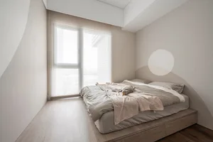 Modern minimalist bedroom featuring a light wood bed frame and soft, neutral bedding.
