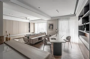 Modern minimalist living room with light wood furniture, gray sofa, and large windows with vertical blinds.