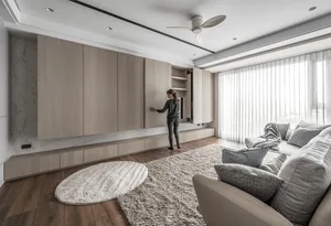A modern, minimalist living room with wooden furniture, marble accents, and large windows.