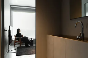 A minimalist home office setup with a wood chair and table, framed by a large window.