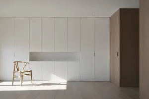 Minimalist-style interior space with wooden cabinets and a Wishbone Chair.