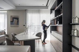 A minimalist living room with a wooden floor, glass shelves, and a sleek design.