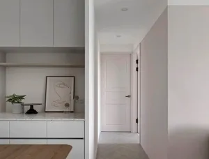 Modern minimalist residential interior with white marble countertops, white cabinets, and wooden flooring.