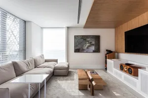 A modern living room with concrete flooring, a beige sectional sofa, and a wooden TV stand with a flat-screen TV.