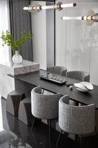 Modern dining room featuring marble table, glass chandeliers, and grey upholstered chairs.