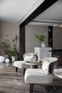 Modern living room with marble floor, grey upholstered chairs, and a round side table with drinks.